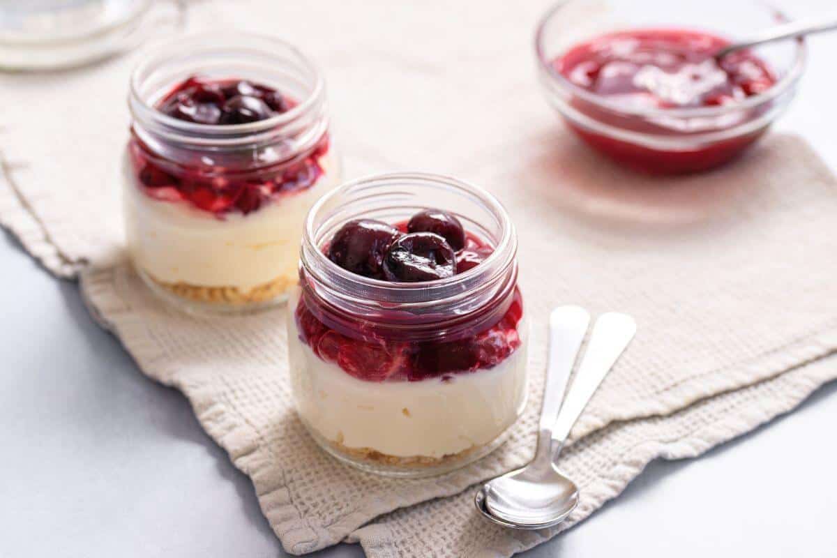 Cheesecakes in jars with cherry topping.