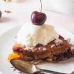 side view of slice of cherry cobbler with ice cream.