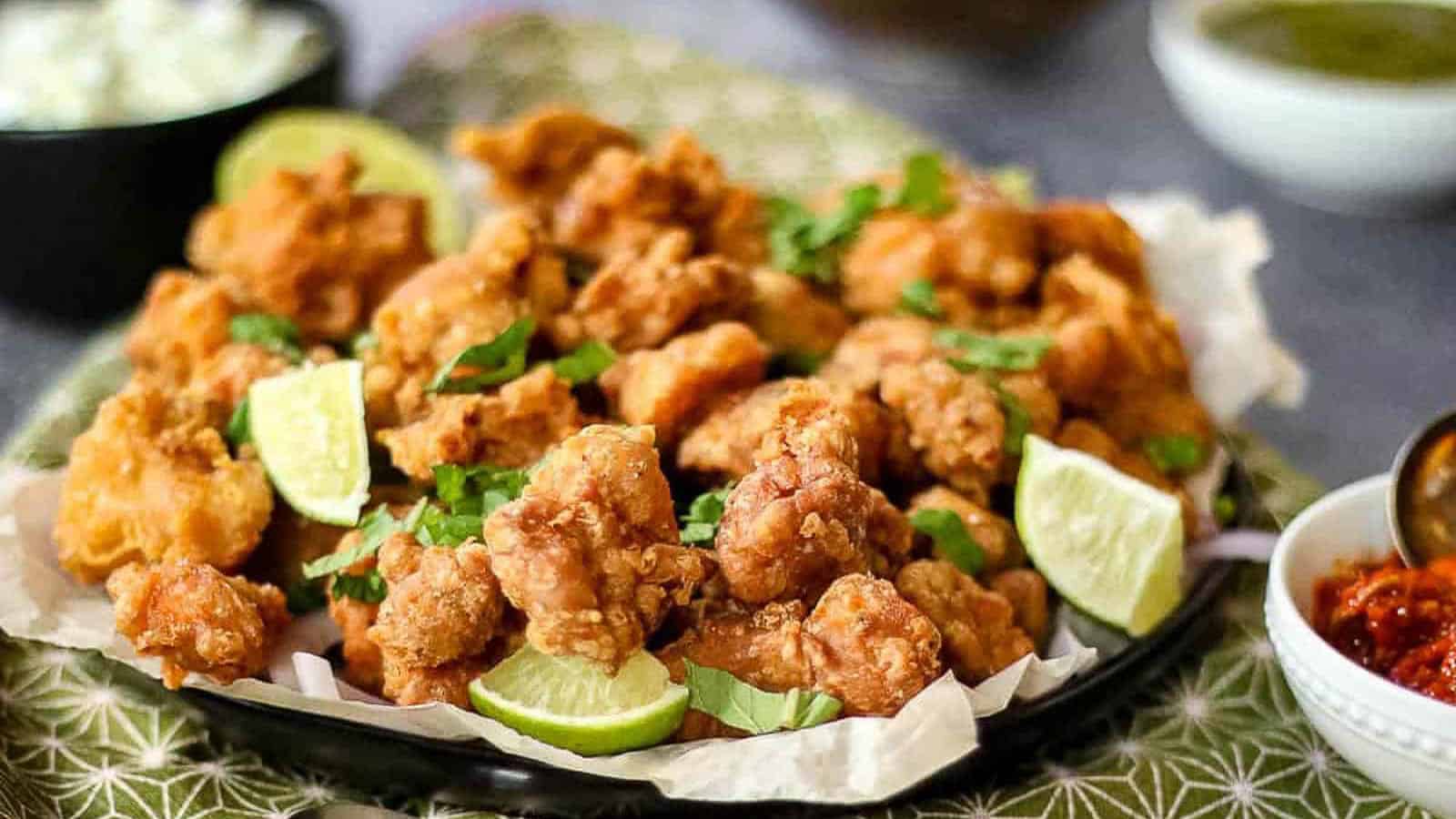 Low angle shot of chicken pakora on a plate with a green napkin.