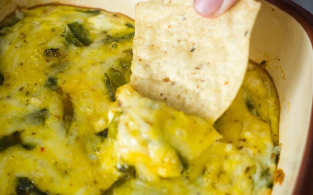 Dipping a tortilla chip into chile relleno casserole.