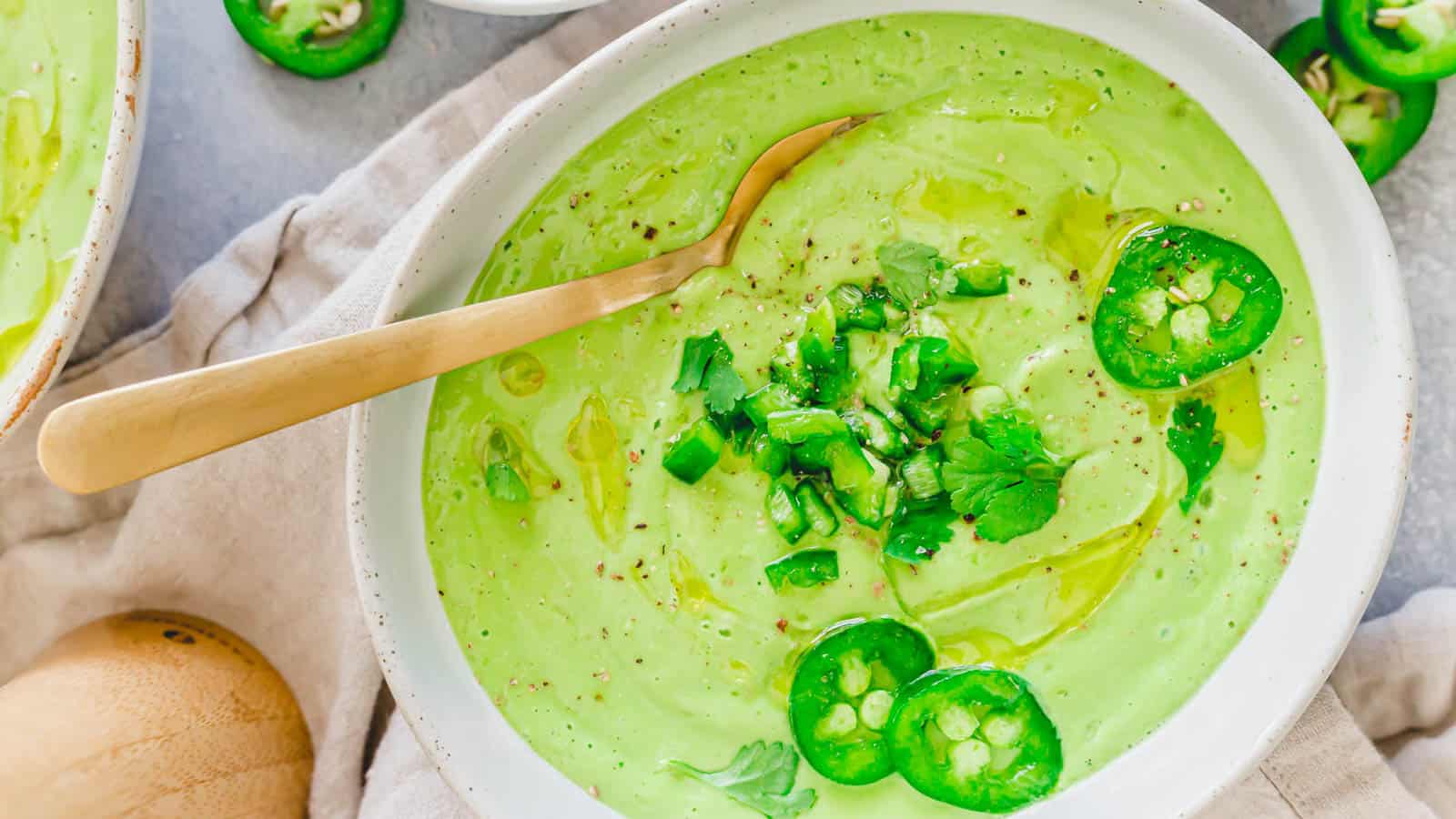 Cold avocado soup garnished with diced jalapeno, cilantro and olive oil.