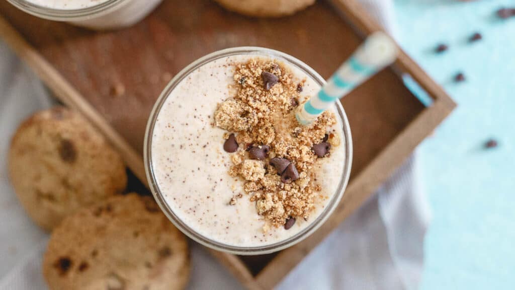 Chocolate chip cookie milkshake in a cup with blue and white straw.