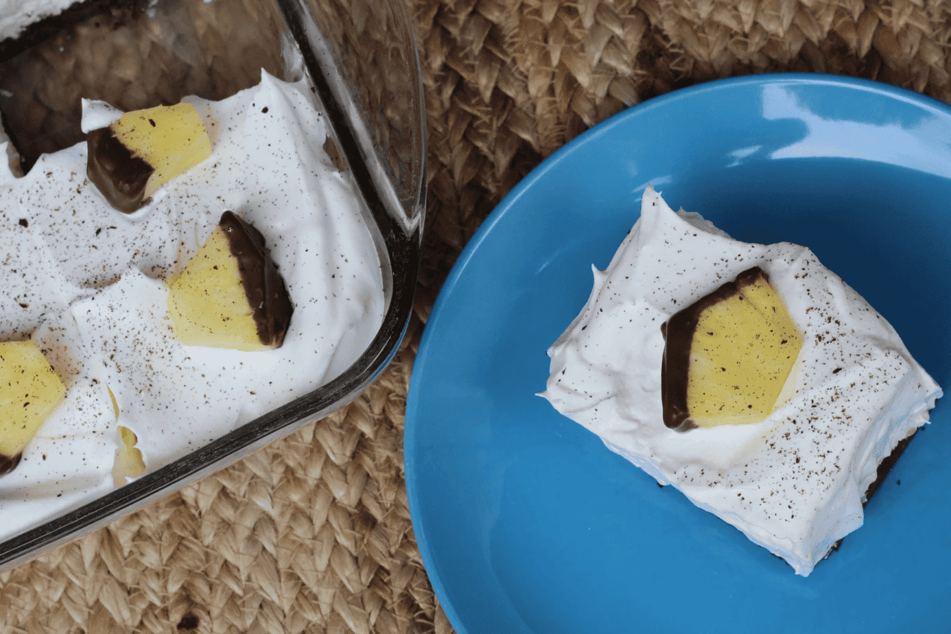 a piece of chocolate covered dessert on a plate next to a pan of dessert