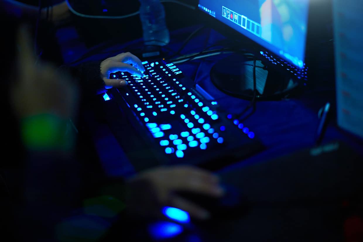 Image of hands on a lit keyboard with a computer monitor in the front.