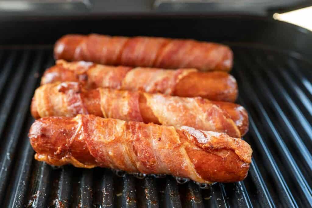 Four hot dogs wrapped in bacon.