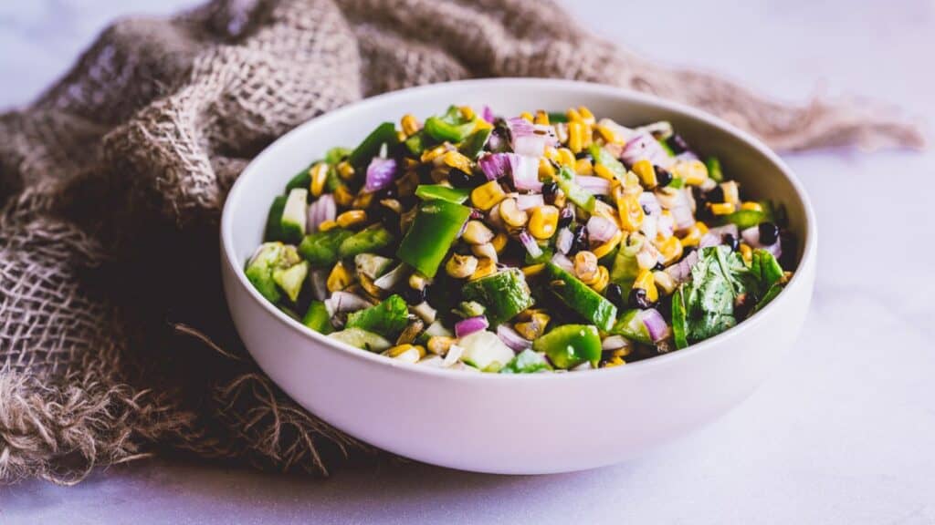 A large white ceramic bowl filled with a grilled corn salad.