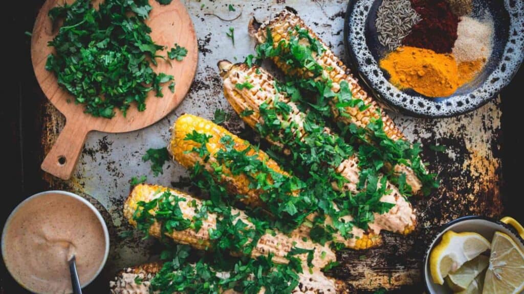 Corn on baking sheet with spices and dipping sauce 