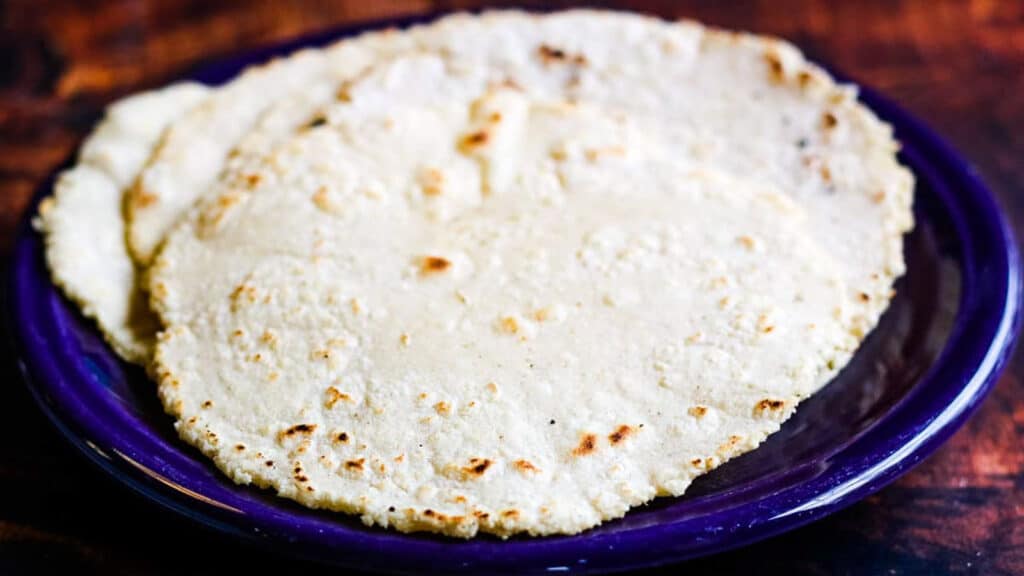 Stack of corn tortillas on a blue plate.