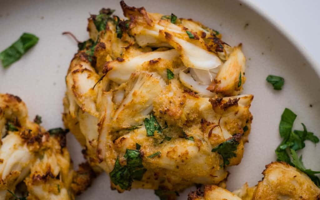 Crab cakes on a white plate with parsley.