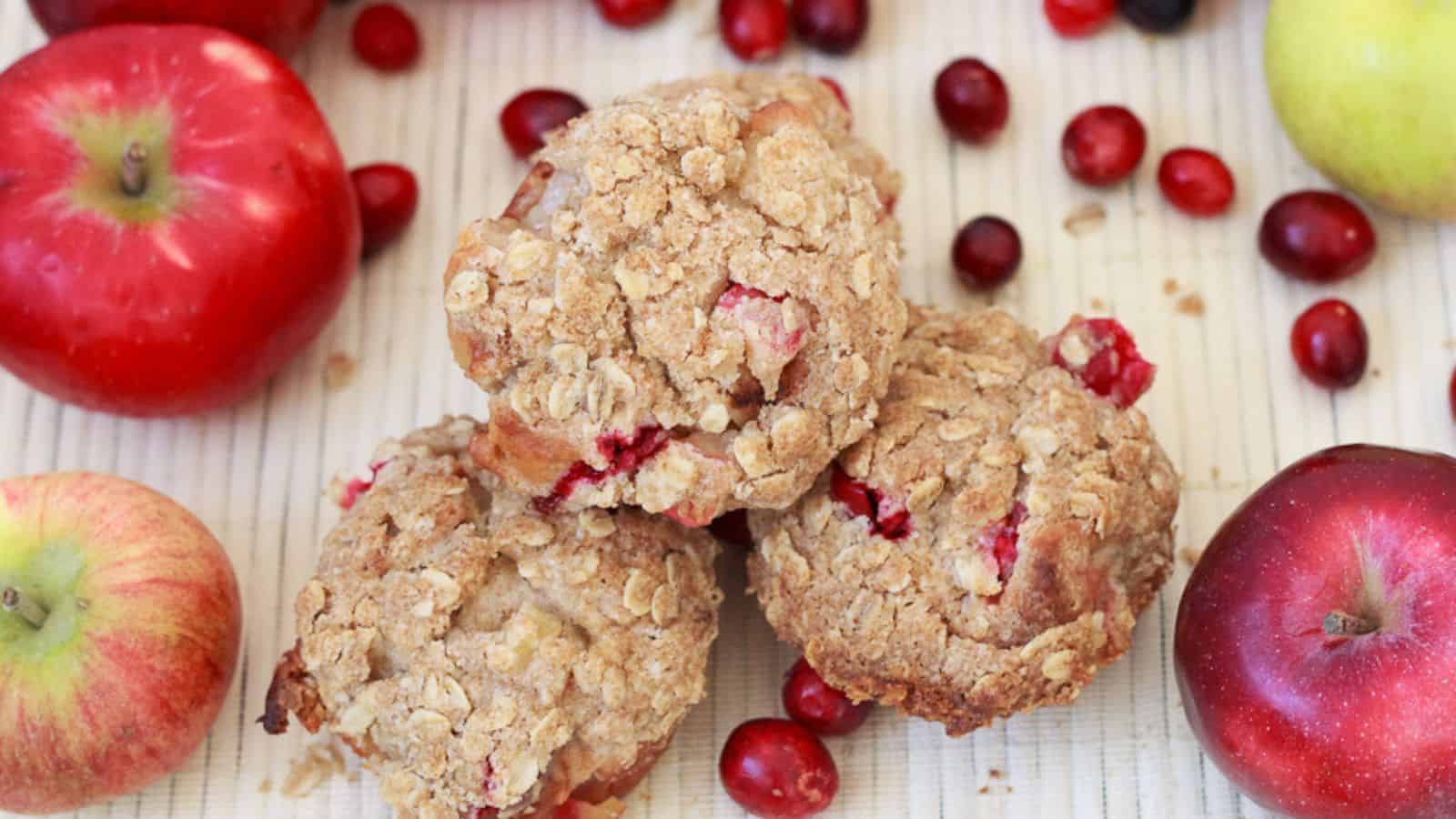 Three apple cranberry muffins on a table.