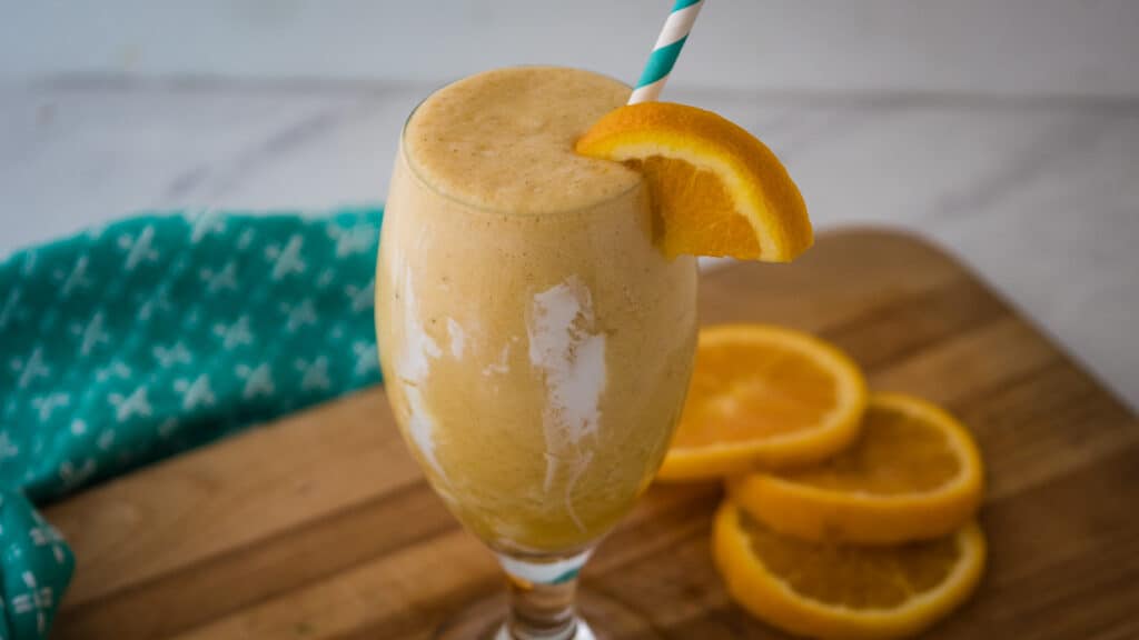 Orange creamsicle smoothie with orange slices and a blue napkin.