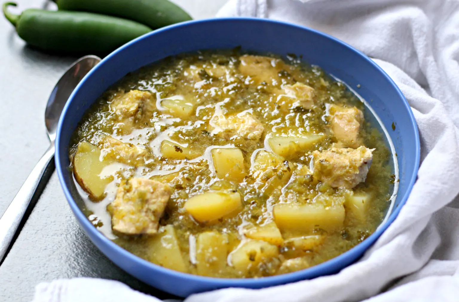 Chicken Verde with Potatoes Soup in a blue bowl with spoon.
