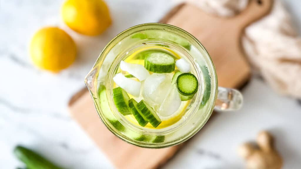 Overhead shot of cucumber lemon ginger water in a glass pitcher.
