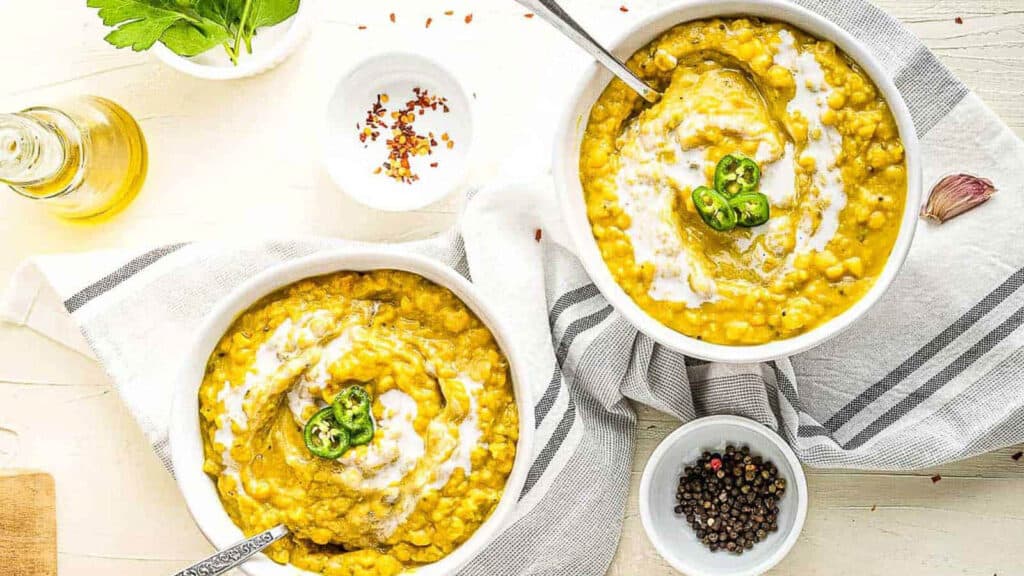 overhead shot of 2 bowls of dal soup garnished with coconut milk and sliced green chiles.