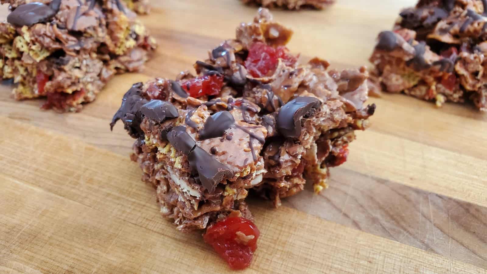 Photo shows a double chocolate cherry cereal bar on a wooden board with more in the background.