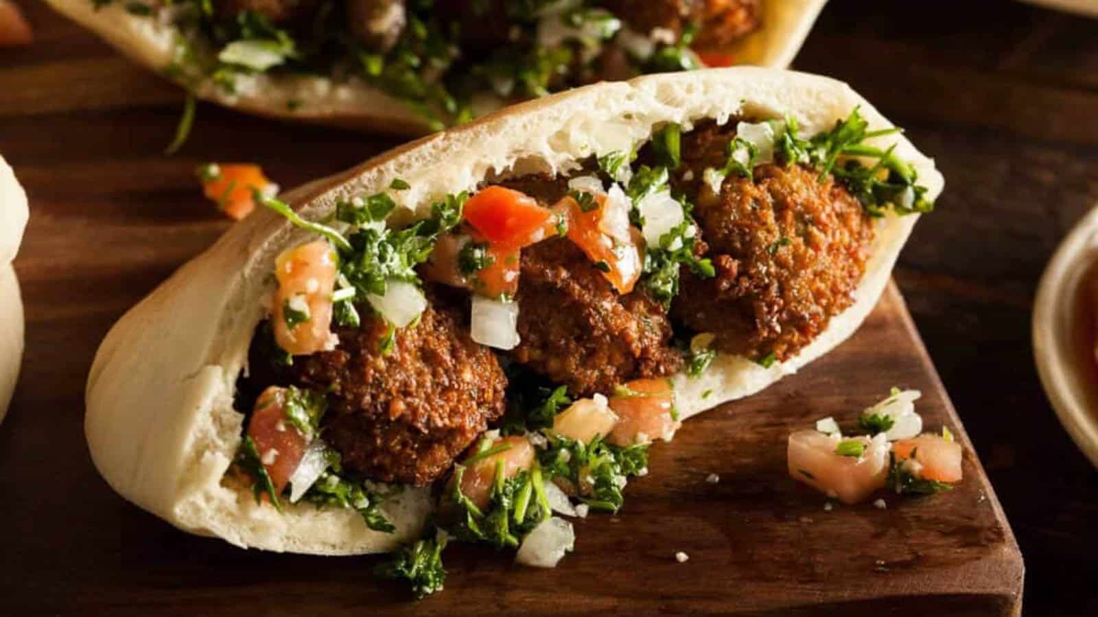 Low angle shot of falafel in a pita with parsley and tomatoes.