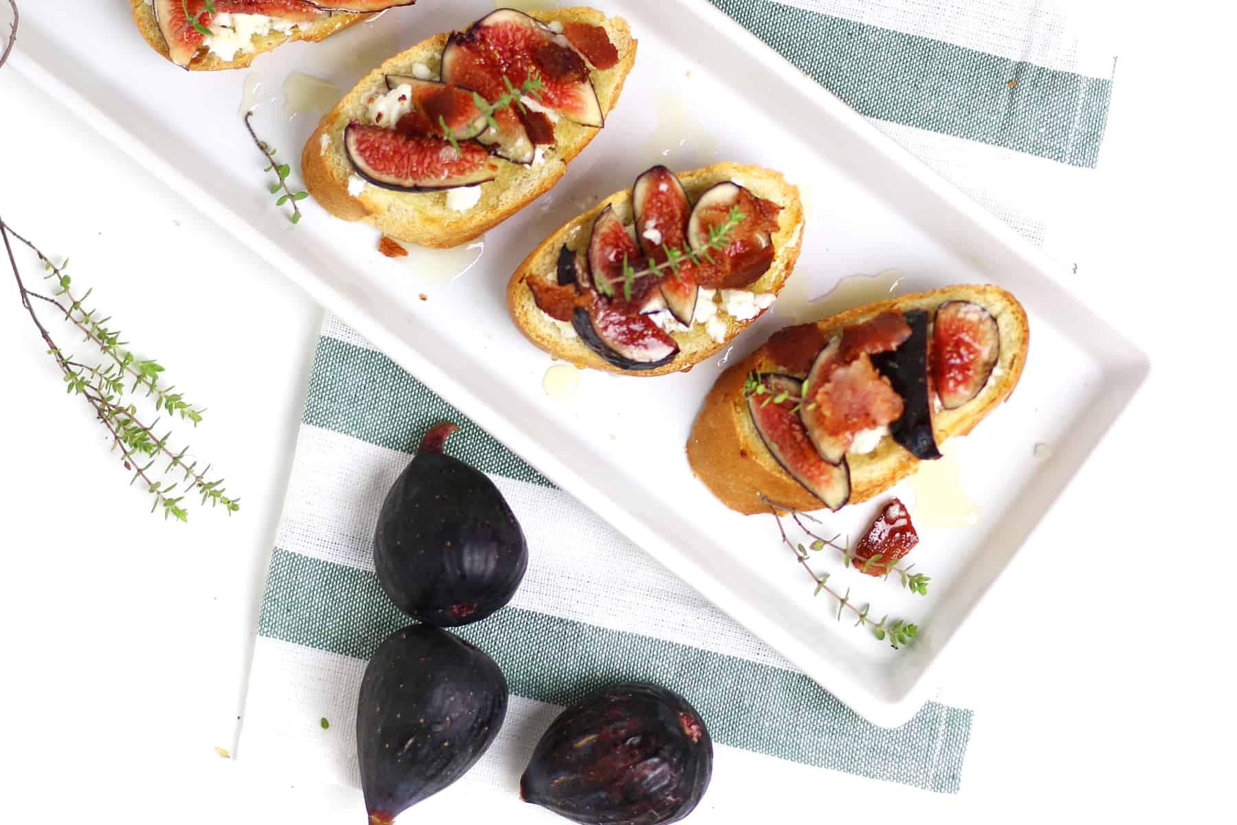Fig and goat cheese crostini on a white tray.