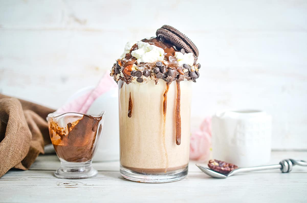 Cookie Dough Milkshake with a spoon and syrup in the background.