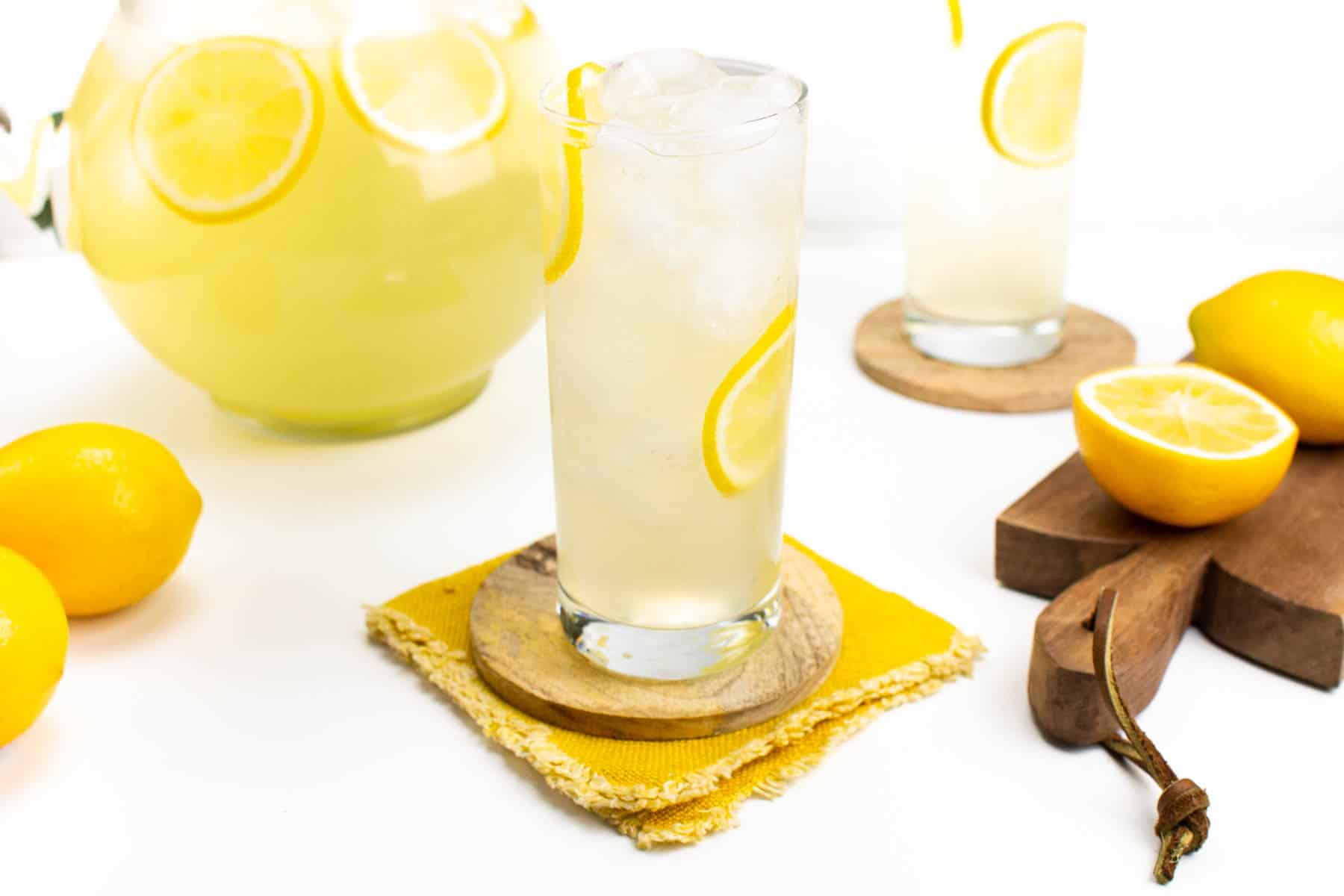 a glass of lemonade on a yellow fabric coaster.