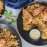 Overhead shot of 3 plates of chicken biryani.