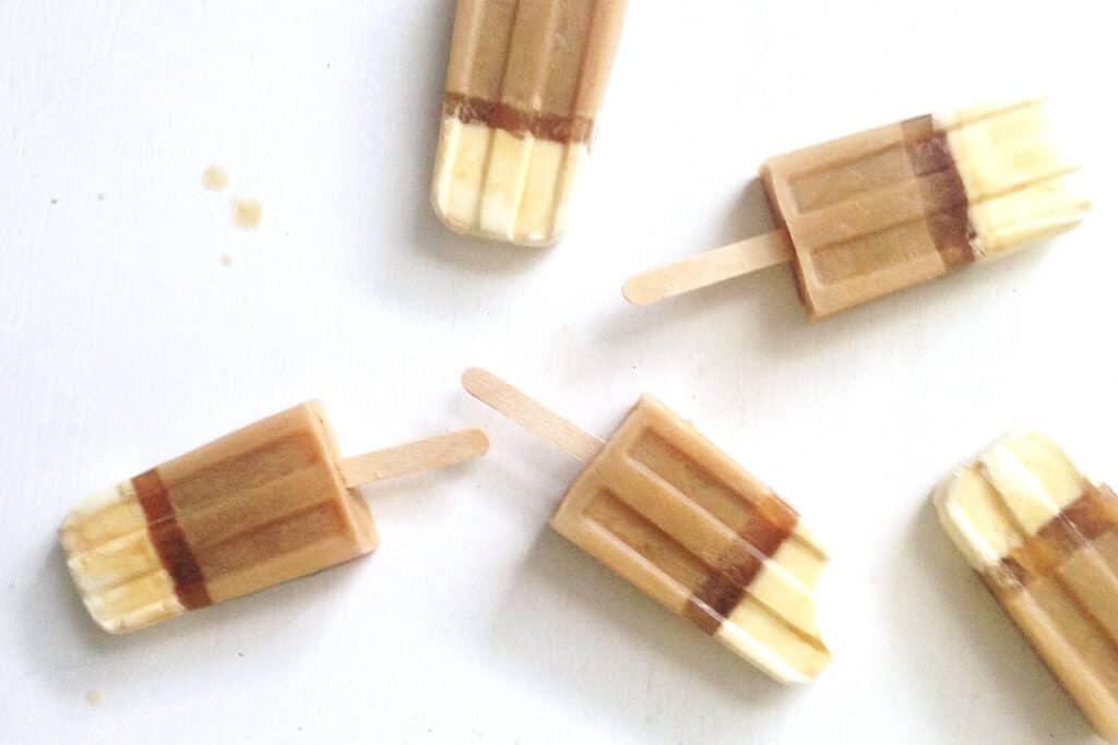 5 Irish coffee popsicles lying on a wood table.