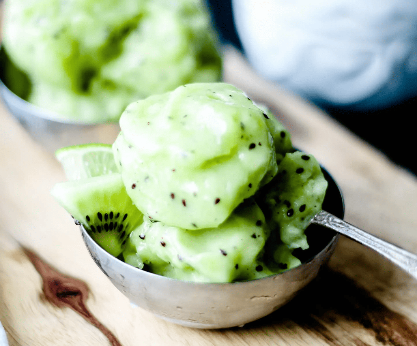 A bowl of kiwi sorbet on a wooden board.
