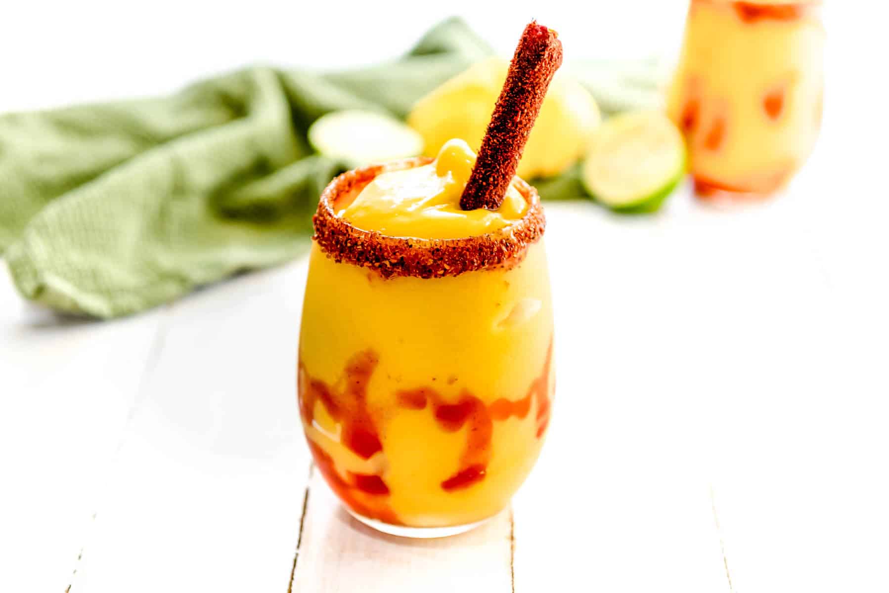 A mangonada in a stemless wine glass on a wooden backdrop.