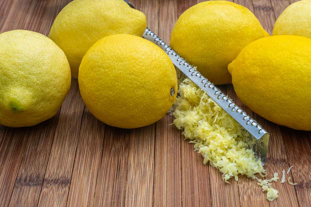 Whole lemons on the wooden board with zest.