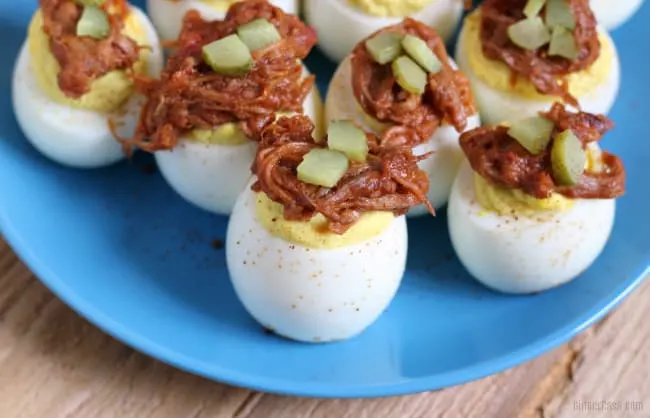Pulled pork deviled eggs on a blue plate.