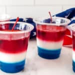 Red, white and blue jello layered in clear plastic cups.