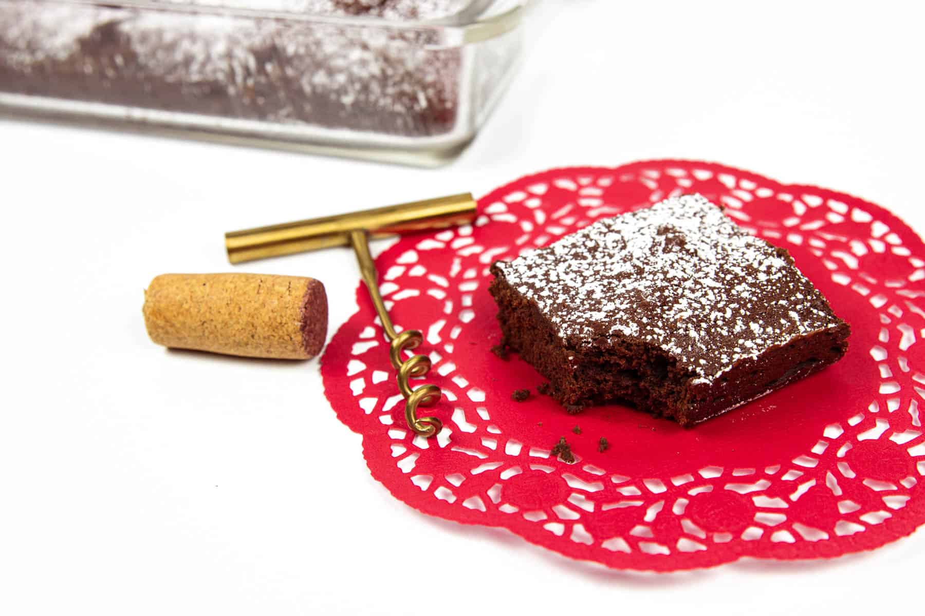 Red Wine Brownies on a red doilie with a cork screw next to it.