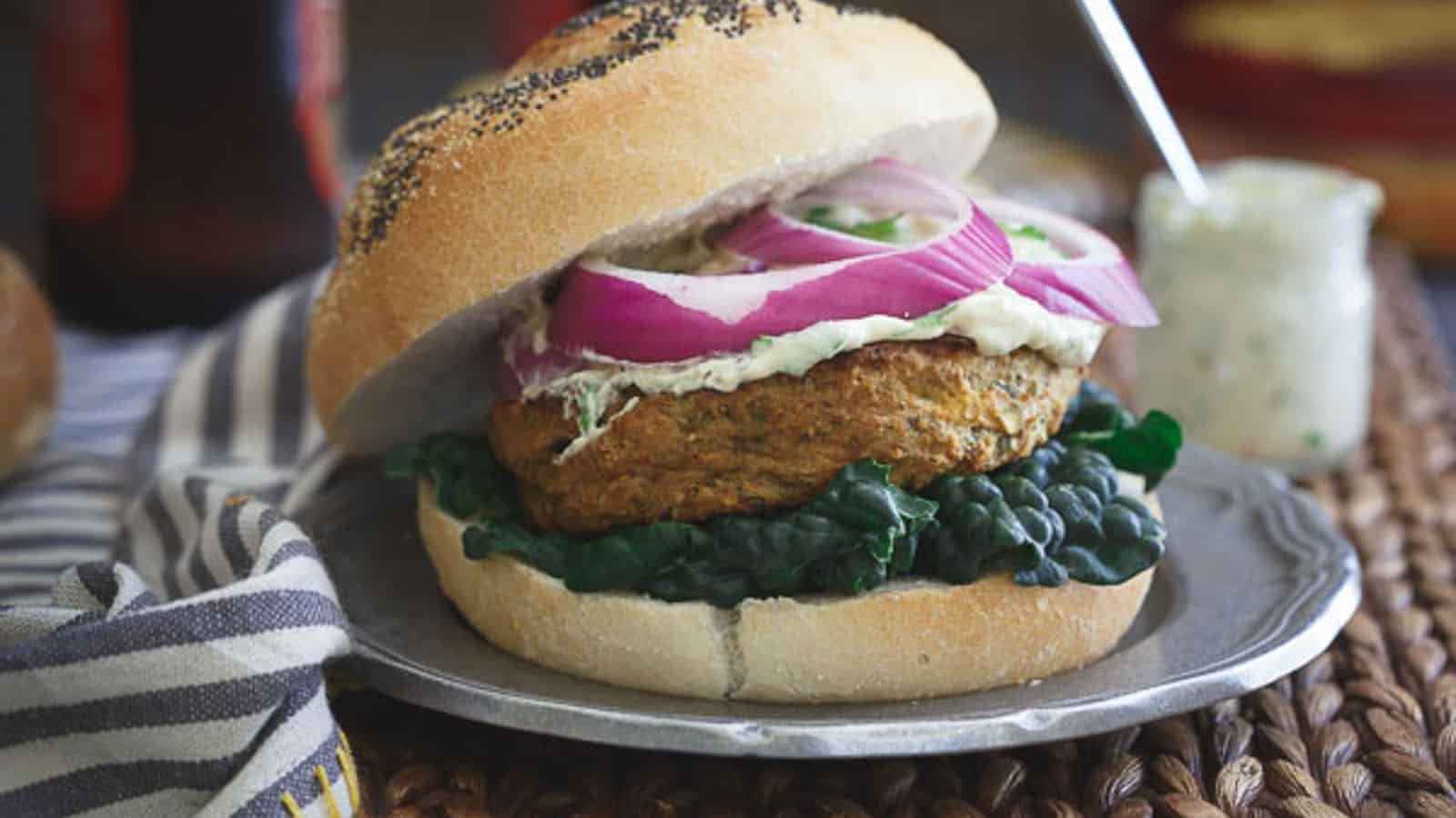 Roasted eggplant curry burger on a bun with kale, red onions and cilantro hummus sauce.
