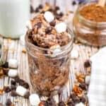 Low angle shot of rocky road ice cream in a canning jar with chocolate chips, marshmallows and nuts scattered about.