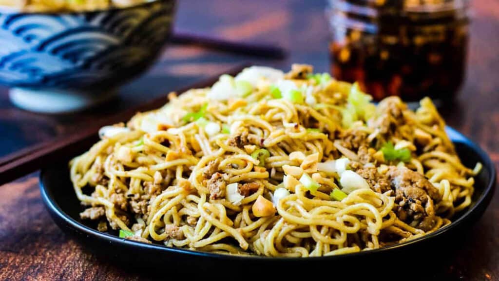 Sesame noodles on a black plate.