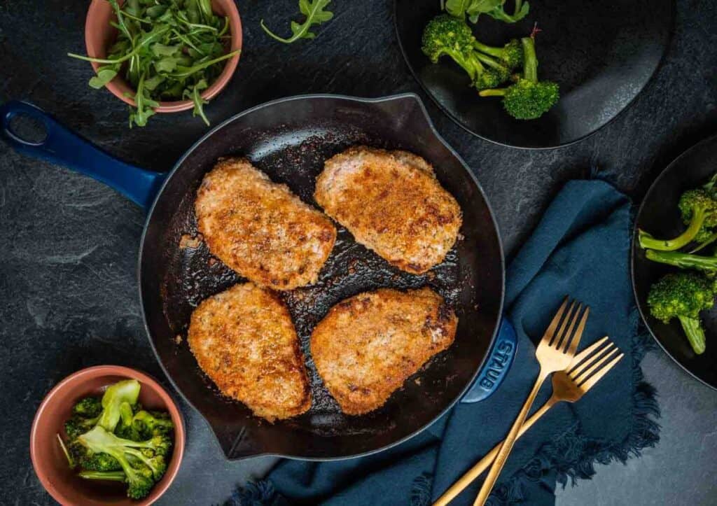 Breaded pork chops in skillet.