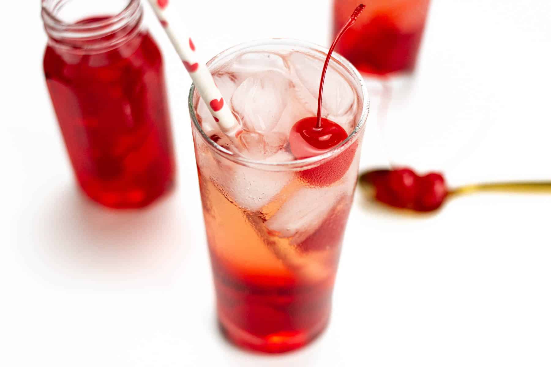 a Shirley Temple with a straw and a cherry on top.