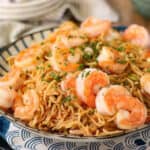 Shrimp yakisoba on a blue and white striped plate.