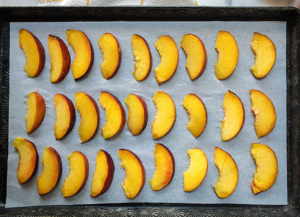 Sliced peaches on a baking sheet.