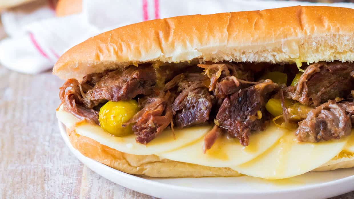 Slow cooker Italian beef on a crusty roll with provolone cheese and peppers.