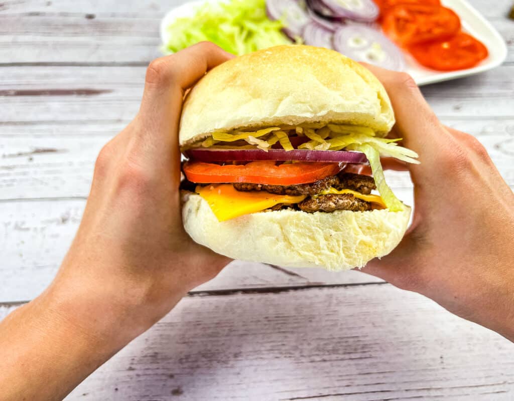 Two hands holding a Blackstone Smash Burger.