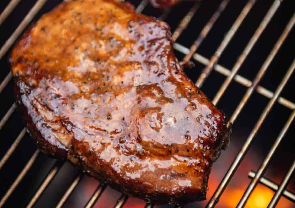 Pork chop on grill grate.