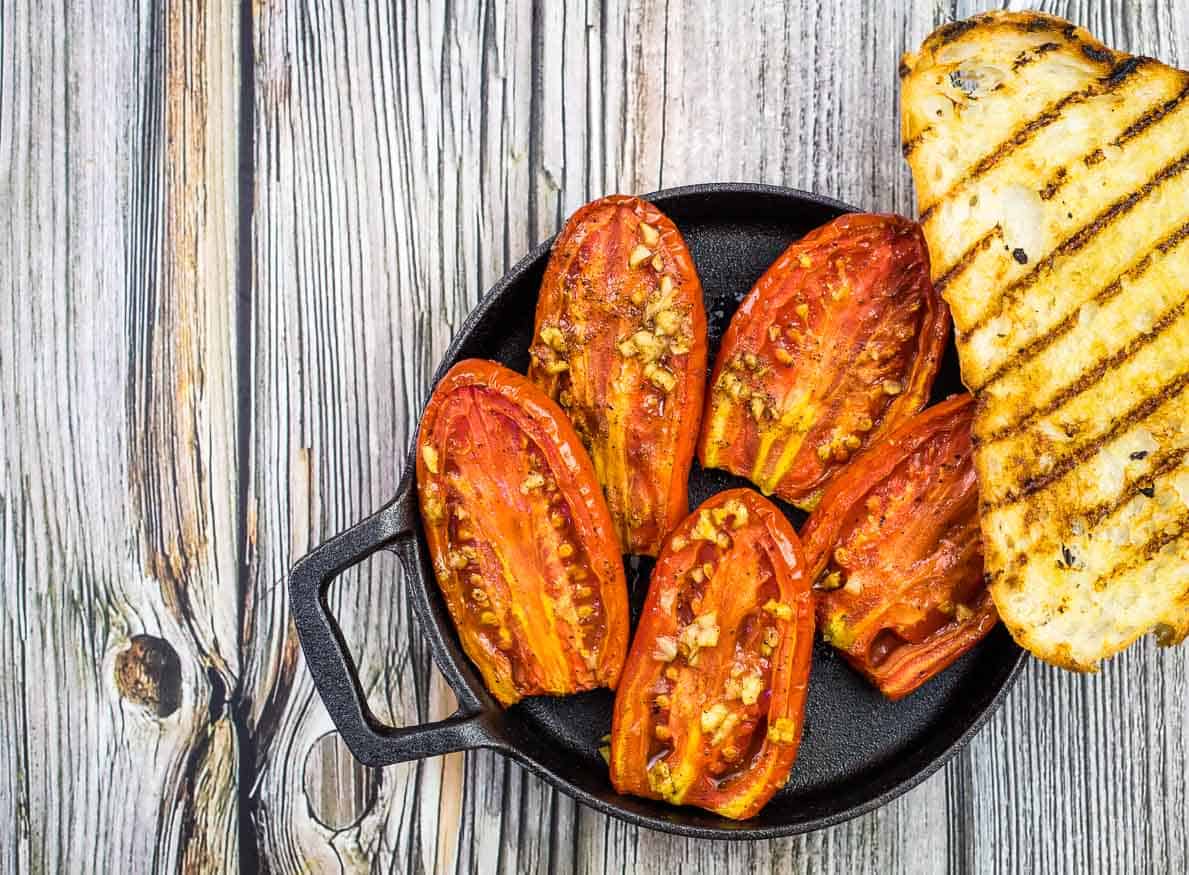 Smoked tomatoes in a dish with grilled bread.