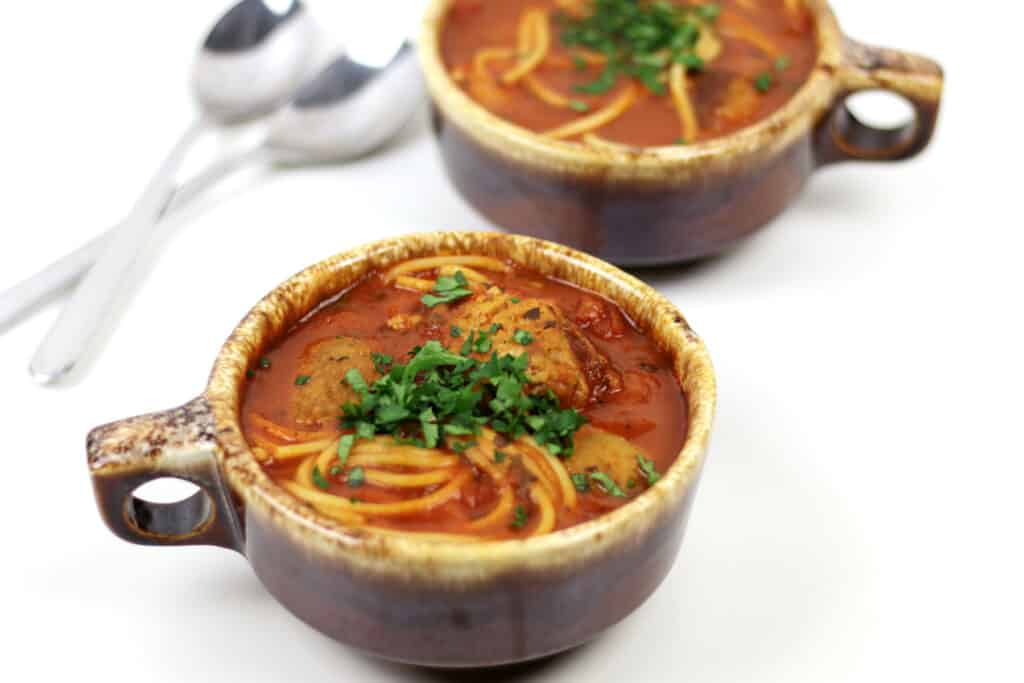 Spaghetti and meatballs soup in a cup.