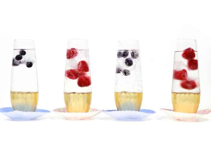 four glasses of sparkling water with berries and balsamic vinegar.