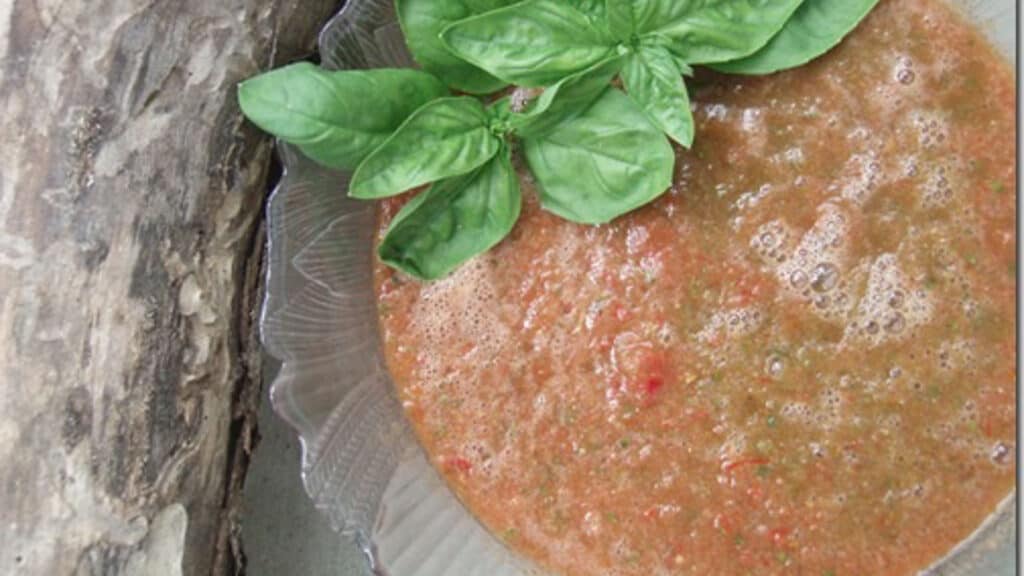 Summer gazpacho with basil garnish in a glass bowl.