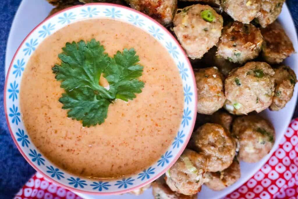 Thai red curry stuff in a bowl with meatballs on the side.