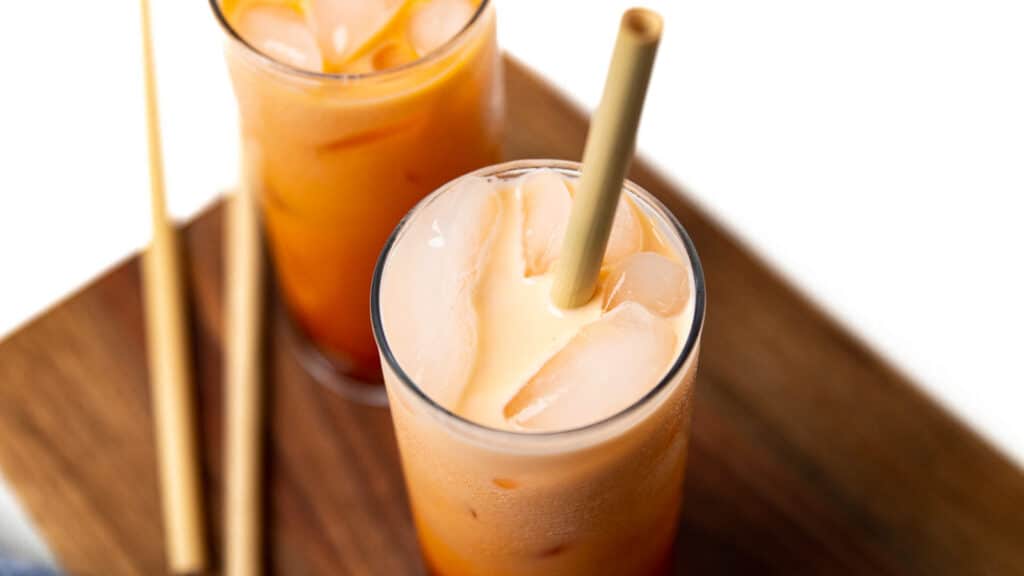 a top view of two glasses of thai iced tea with milk added.