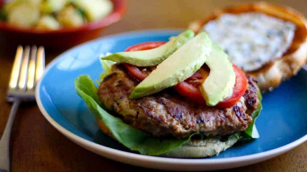 Chipotle turkey burger with avocado on a blue plate.