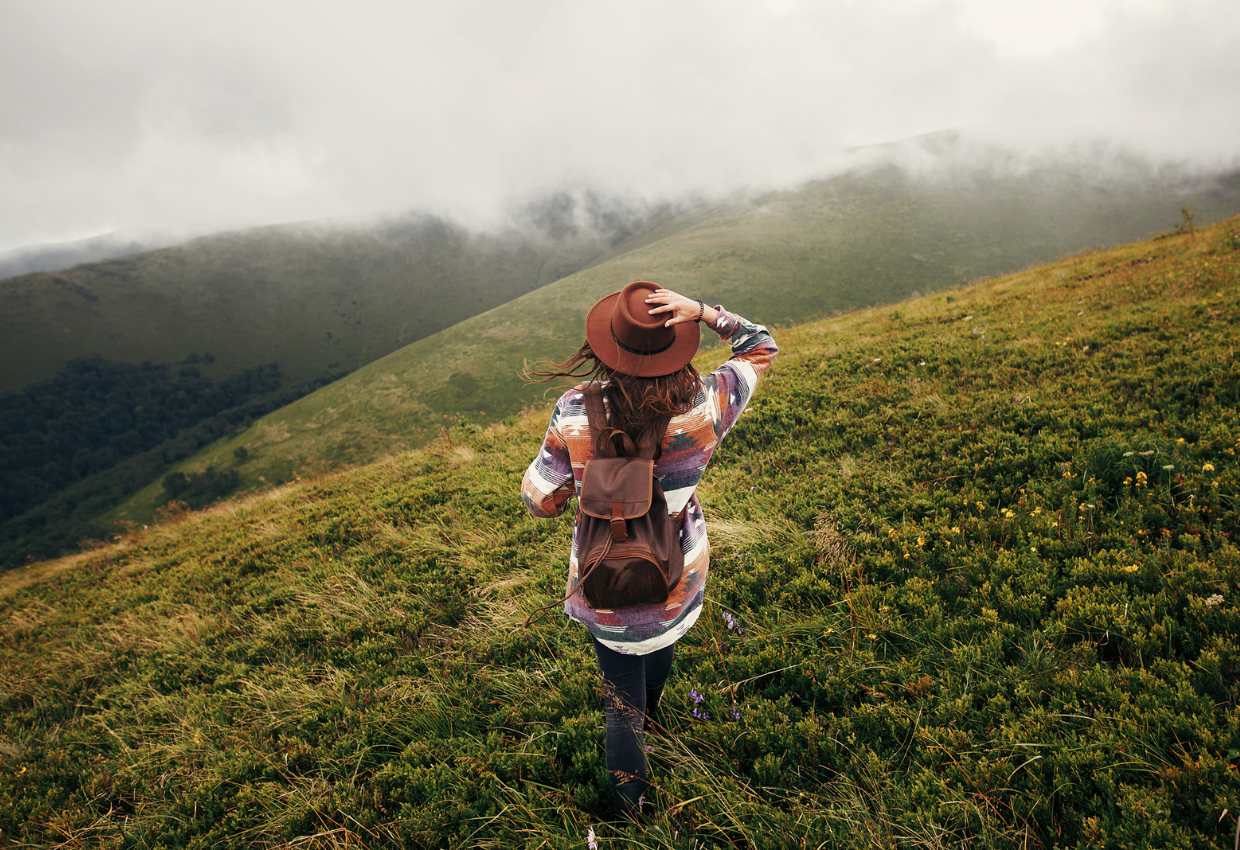 A woman standing on a green hillside.