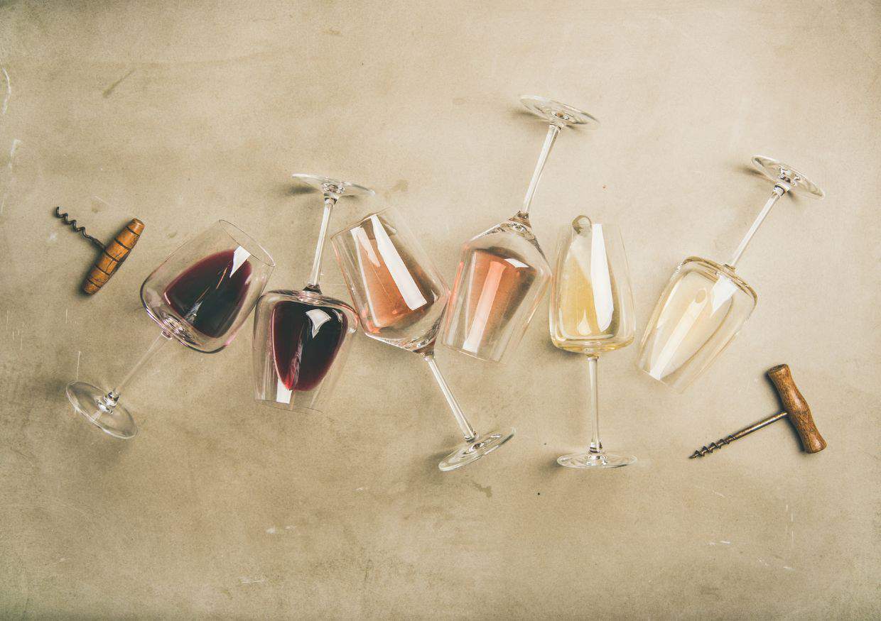 Red, rose and white wine in glasses and corkscrews laid flat.